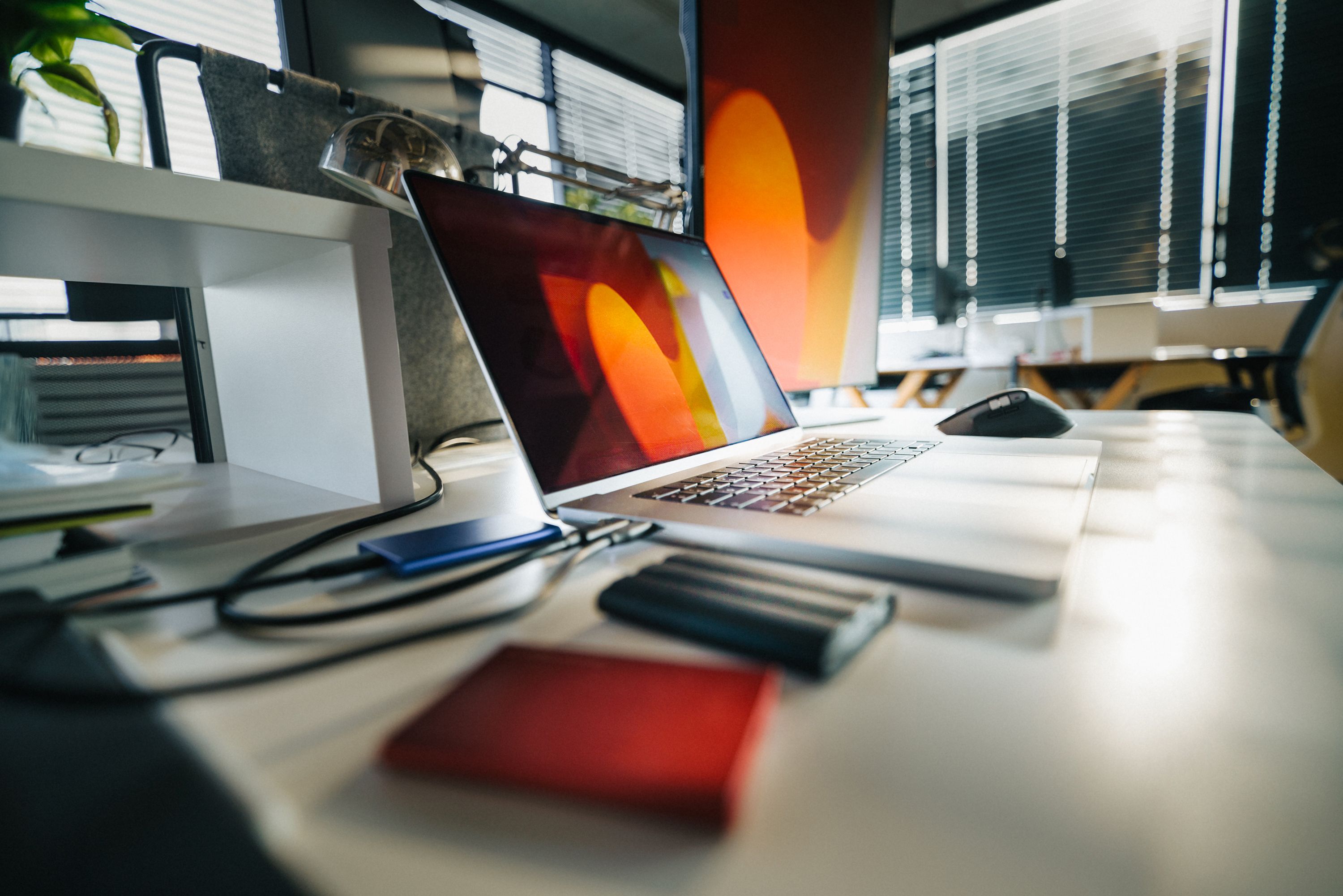 A modern workspace featuring a laptop, external drives, and office equipment on a desk.