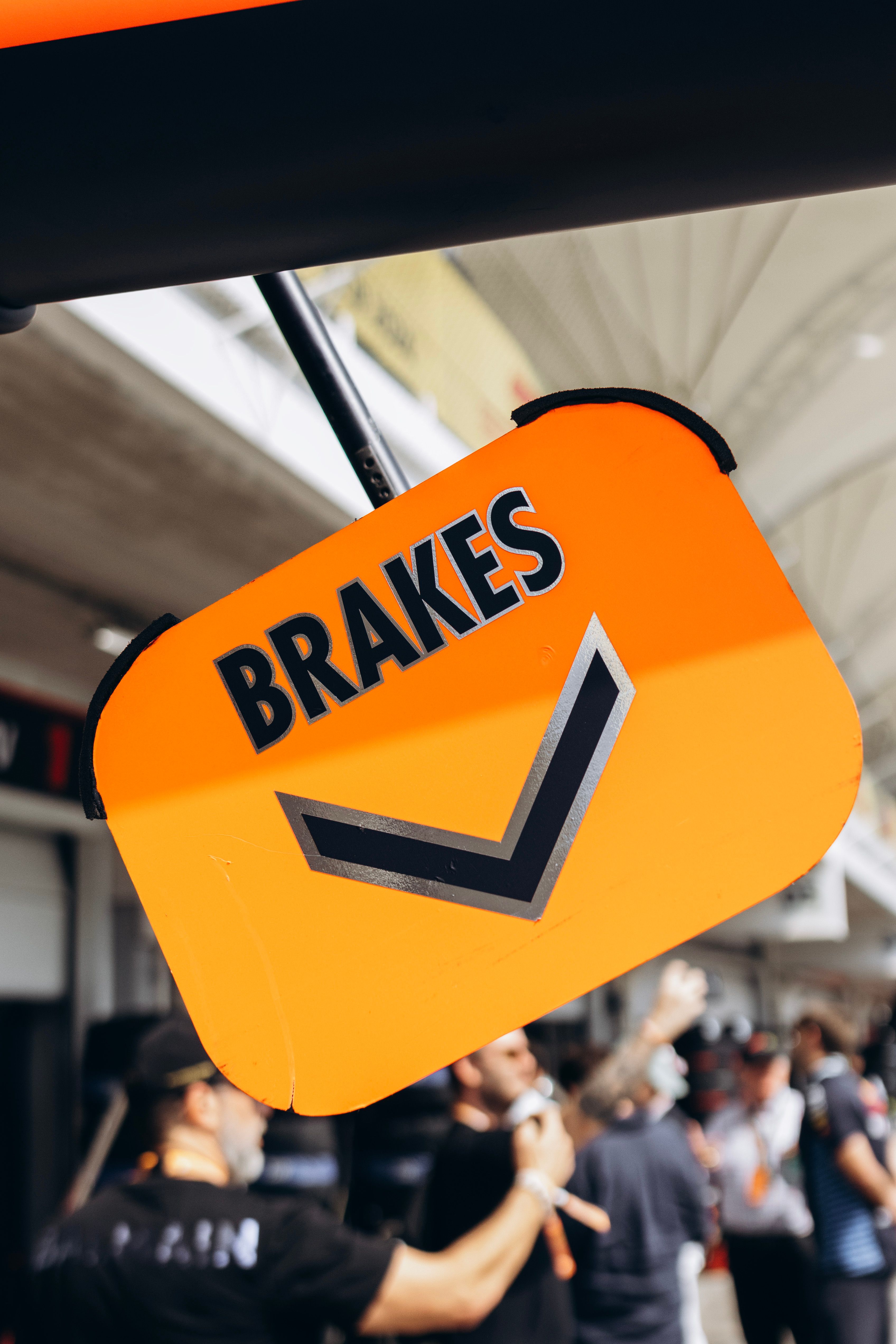Bright orange brakes sign at an outdoor event with blurred crowd in the background.