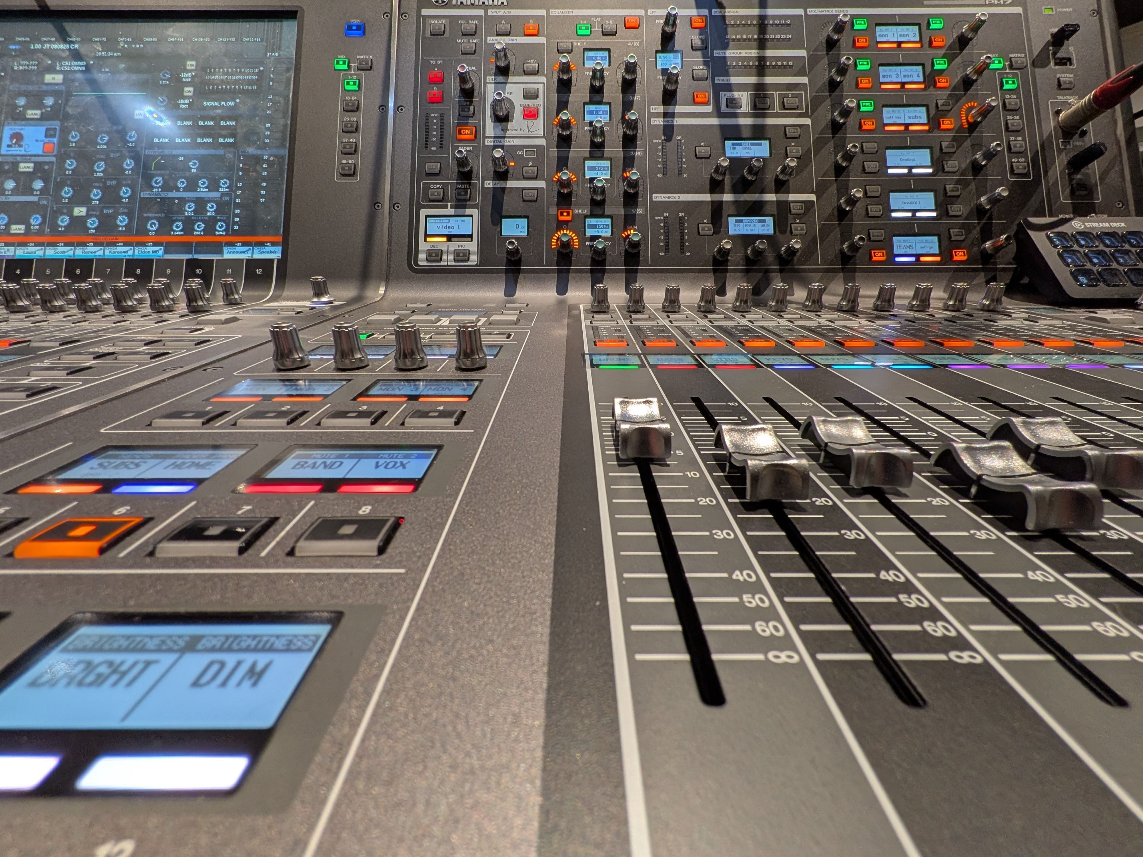 Close-up view of a professional audio mixing console with sliders and buttons in a studio setting.