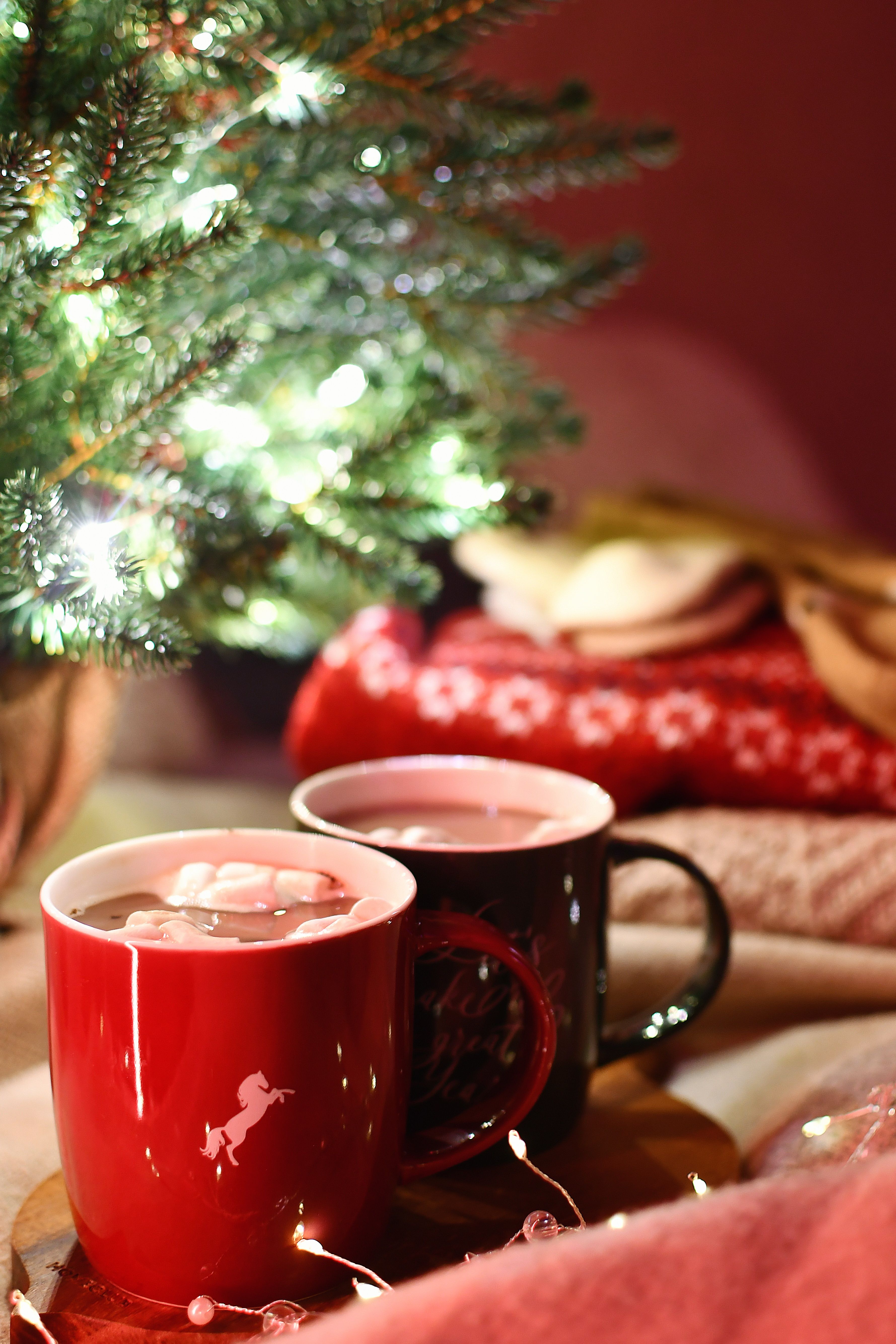 Warm Christmas setting with hot chocolate and a decorated tree, perfect for holiday ambiance.