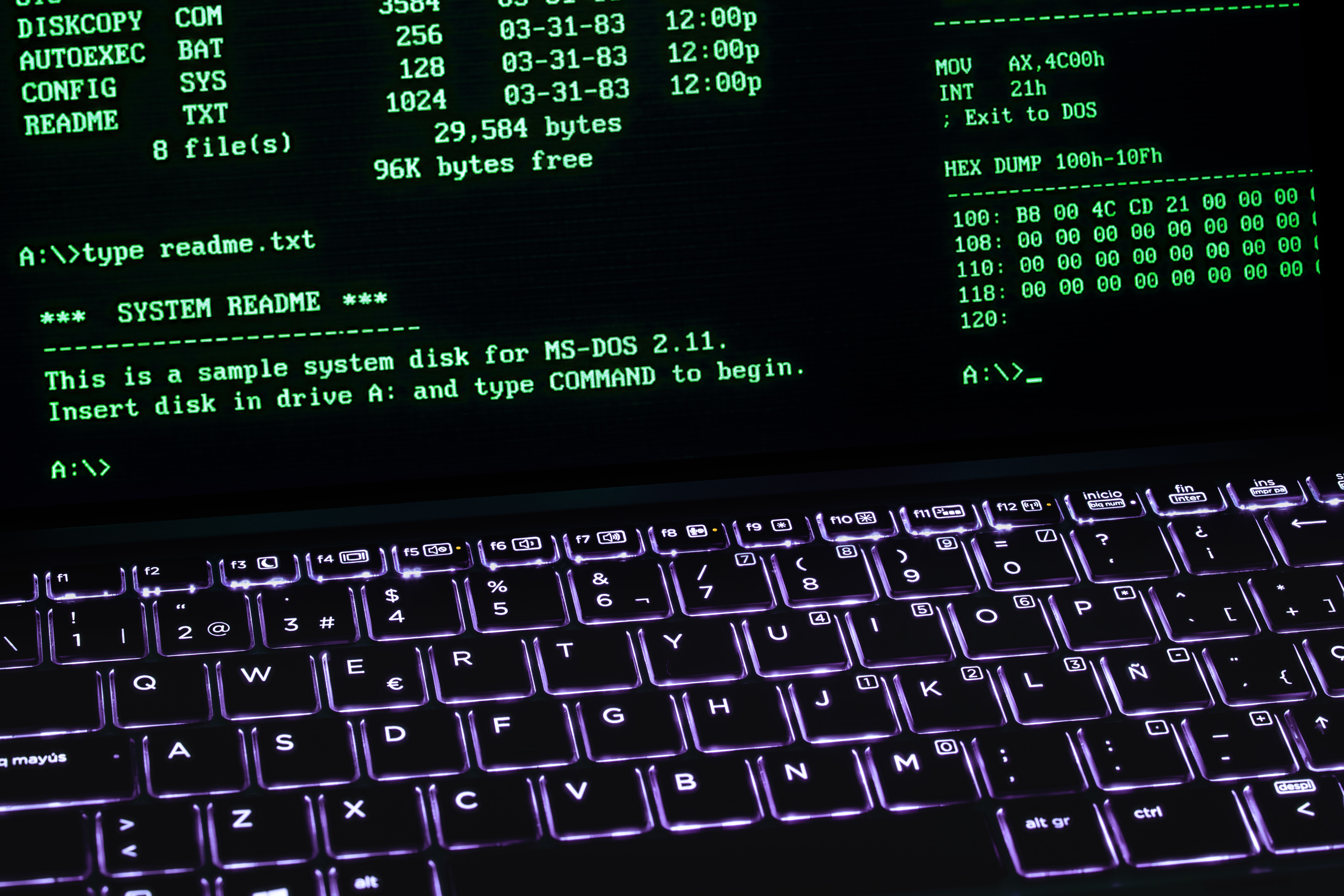 A classic MS-DOS terminal screen displayed on a laptop keyboard with vivid illumination.