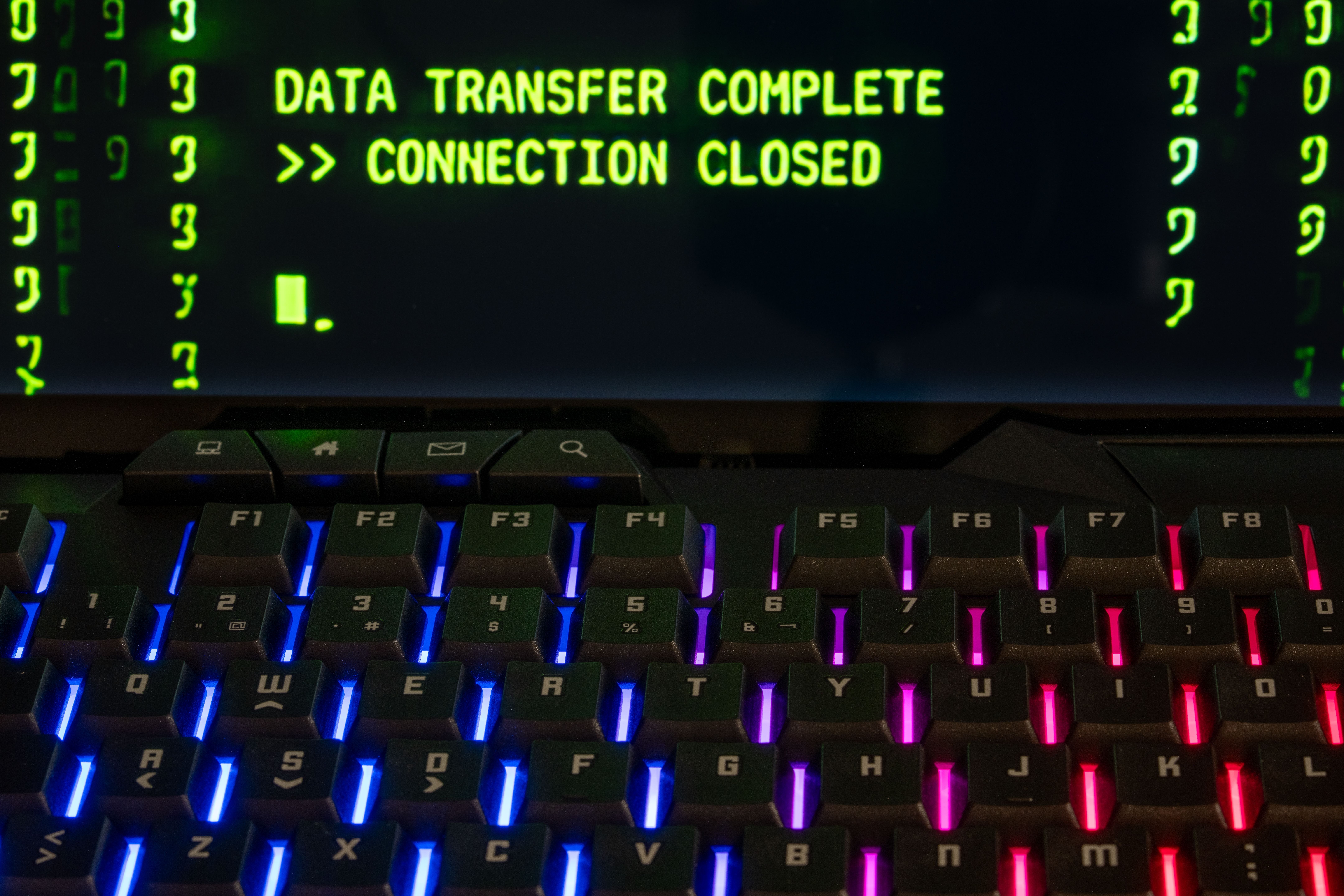Close-up of a RGB lit keyboard with a screen displaying 'Data Transfer Complete'.