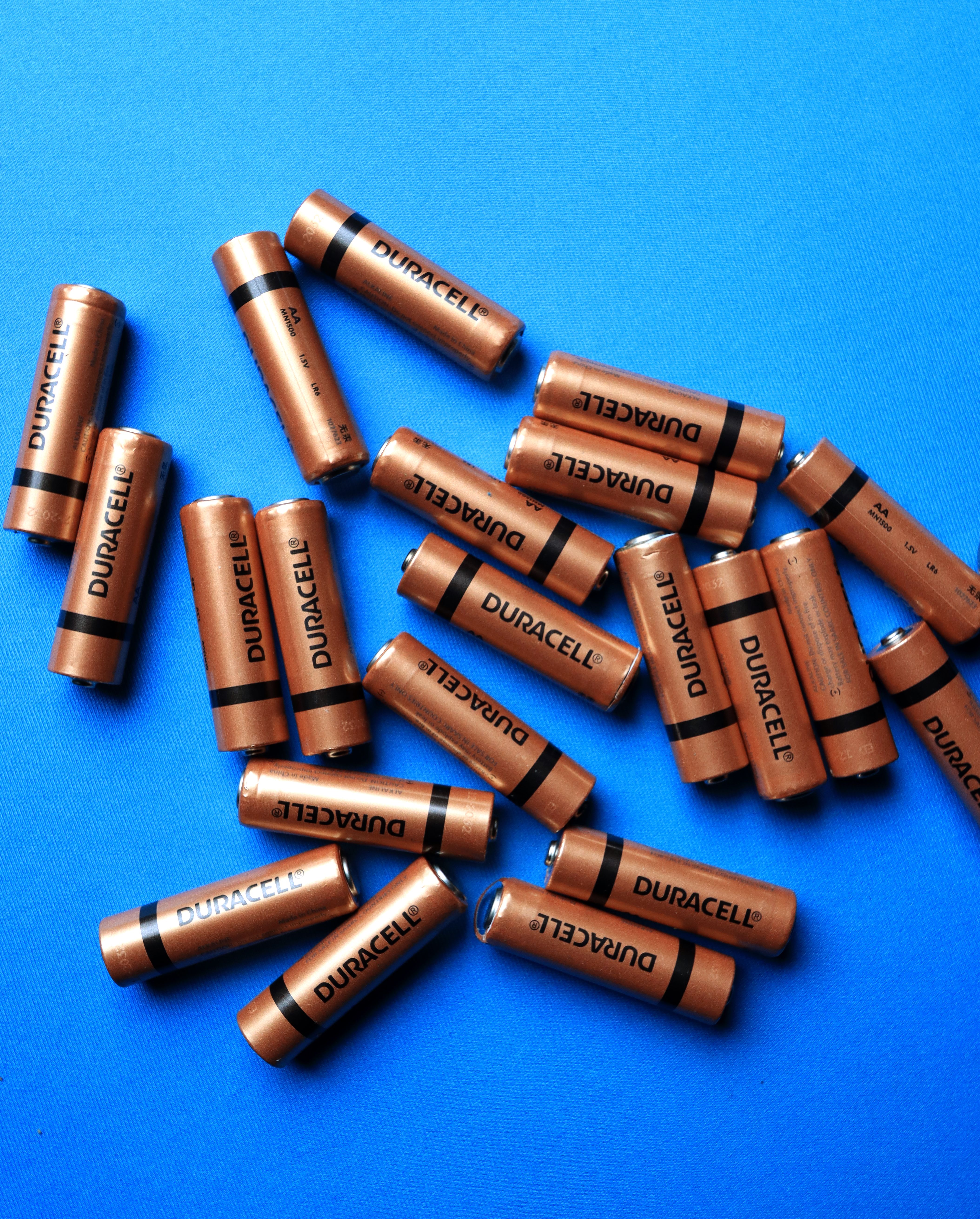A collection of Duracell batteries scattered on a vibrant blue surface, showcasing energy storage.