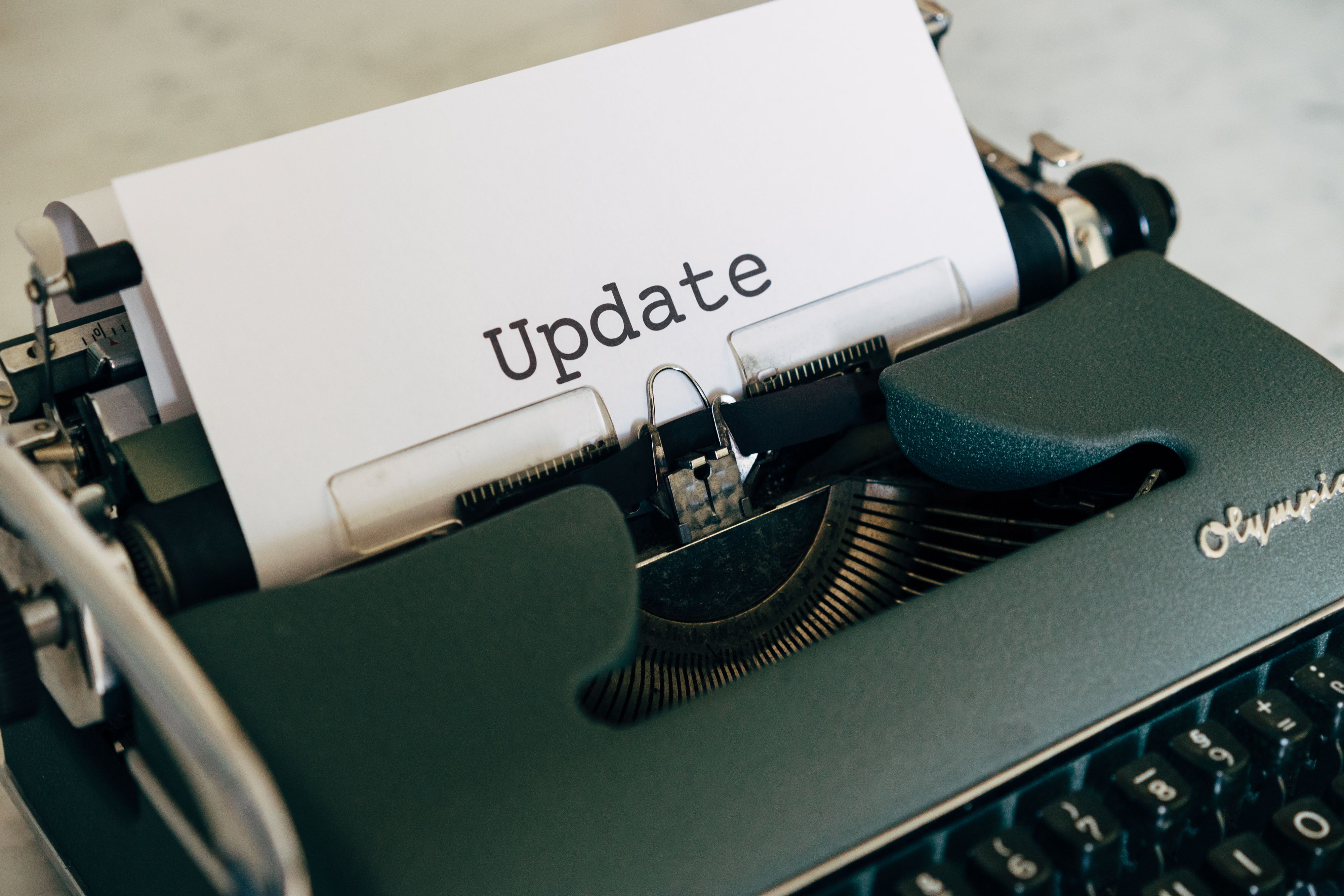 A close-up of a vintage typewriter typing 'Update' on white paper.