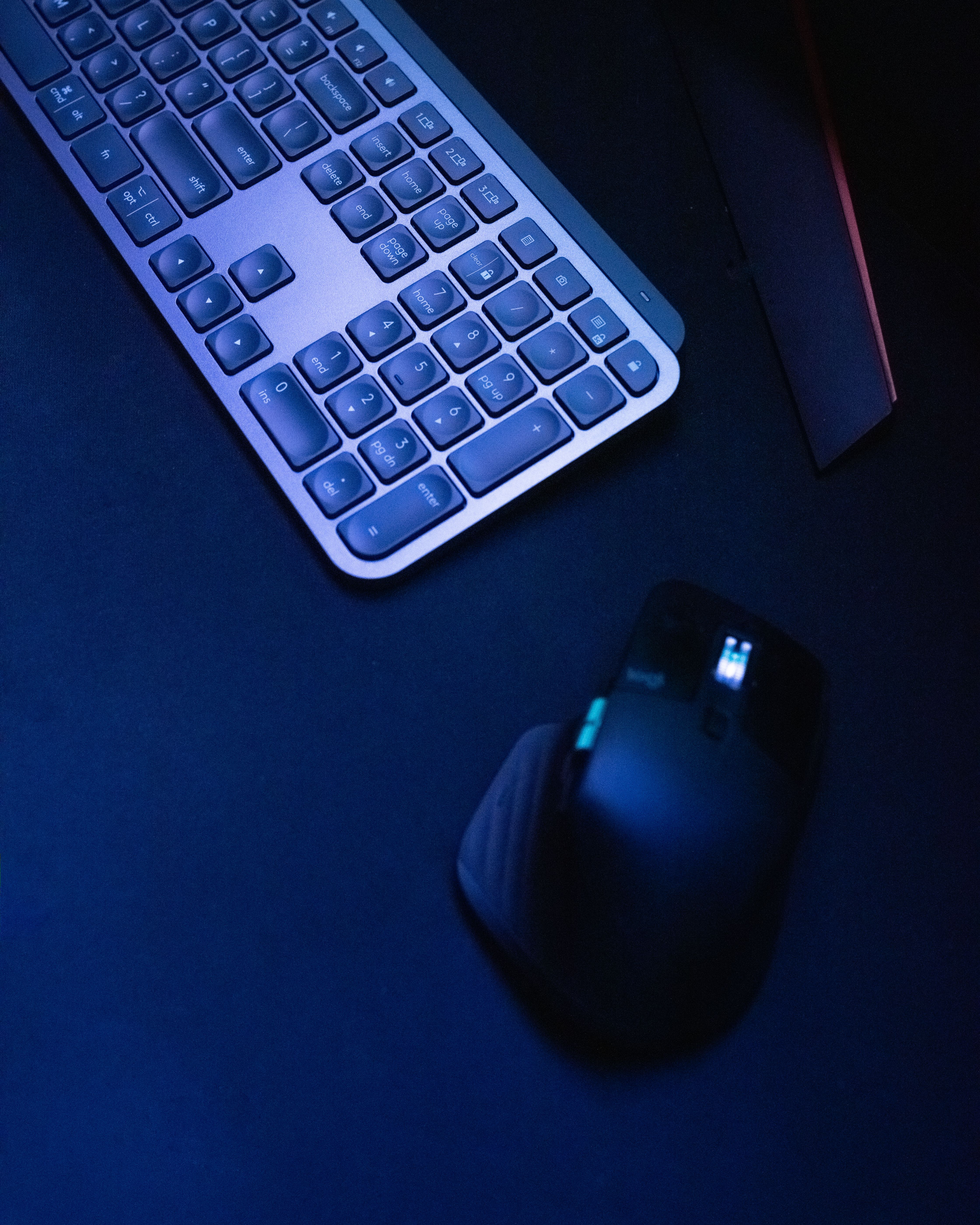 Close-up of a wireless keyboard and mouse on a dark surface, highlighting modern tech design.