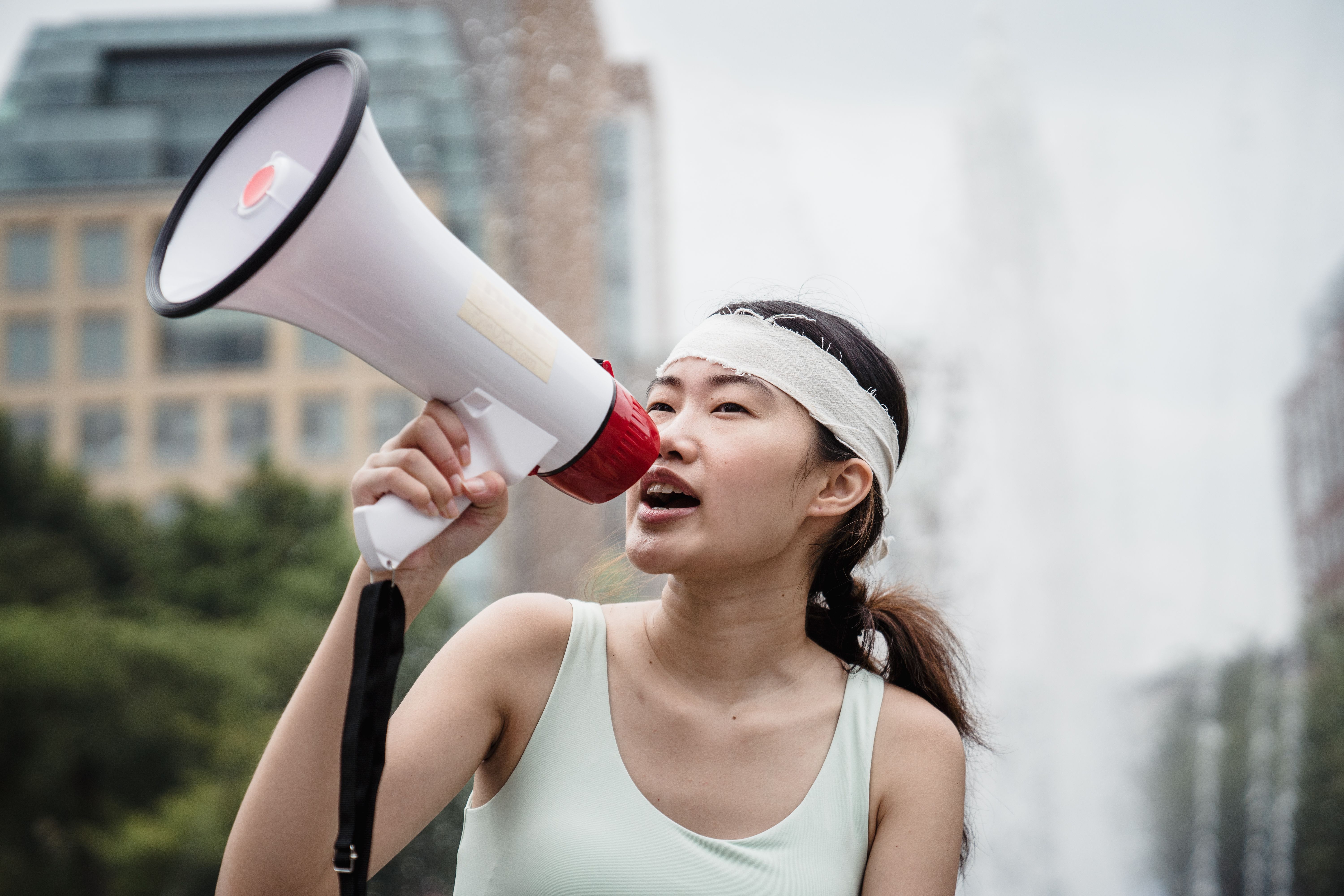 A woman passionately speaks into a megaphone during an outdoor protest, emphasizing activism and nonviolence.